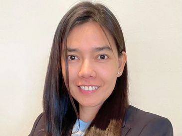 Smiling woman with long dark hair in a blazer.