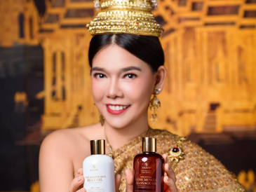 Woman in traditional attire holding two skincare bottles and smiling.