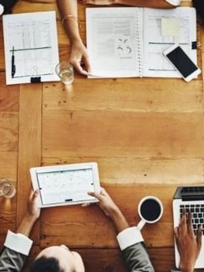 People working with digital and paper documents at a table.