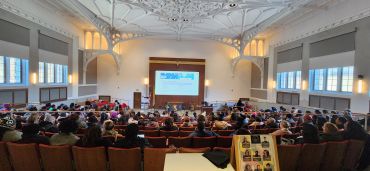 A lecture hall filled with people attending a presentation by CEO and Clinical Director Dr. Dicks