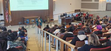 Speaker addressing audience in a lecture hall.