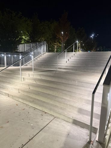 Illuminated concrete stairs with metal railings at night.