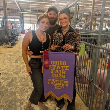 Three people proudly hold an Ohio State Fair 2026 champion banner.