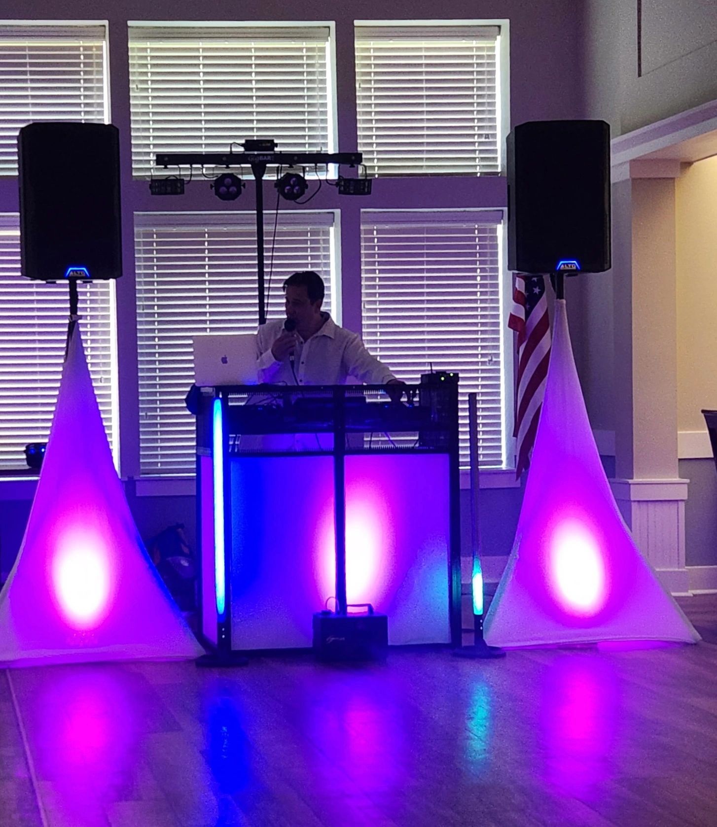DJ performing at an event with purple lighting.