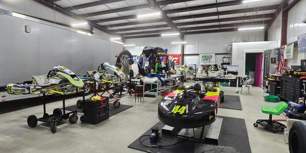A spacious workshop with go-karts and racing equipment being prepared.