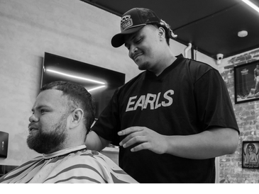 Barber giving a haircut to a seated client in a modern barbershop.