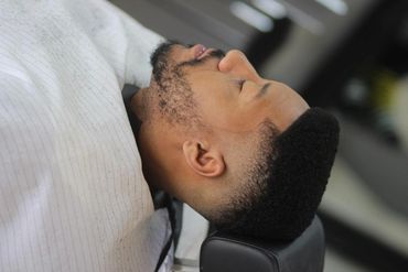 Man with a fresh fade haircut resting in a barber chair.