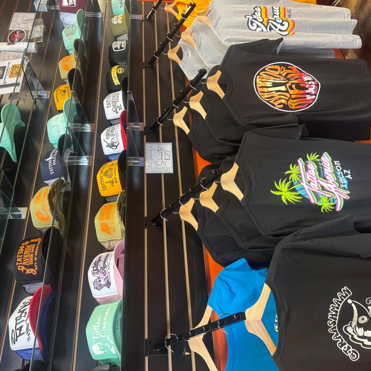 Colorful Tattoo Avenue hats and t-shirts displayed in a store.