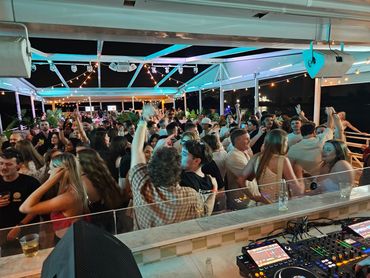 A lively night party with a crowd dancing under string lights.