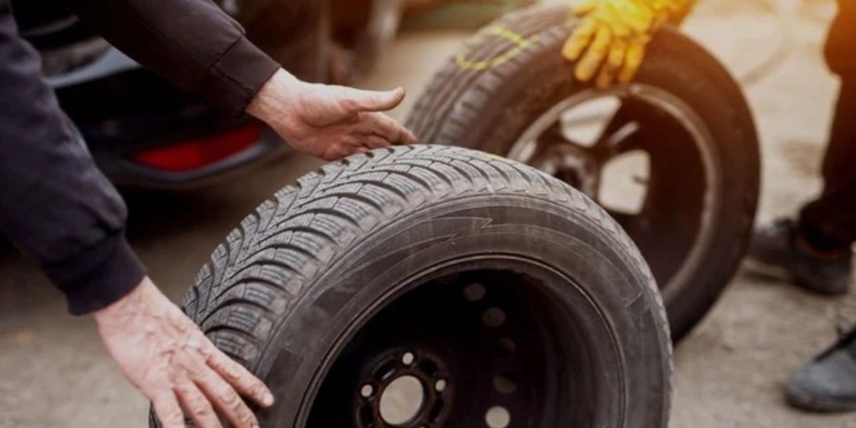 Two people handling car tires during a tire change or maintenance.