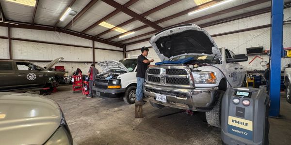 Busy auto repair shop with several trucks being serviced and their hoods open.
