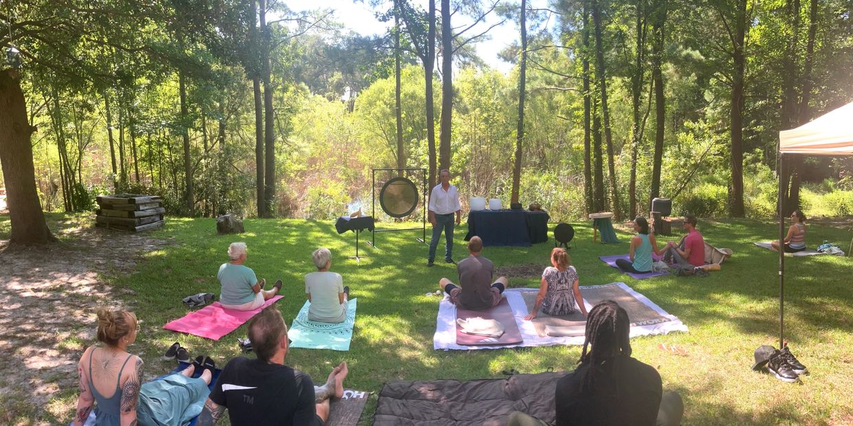 Outdoor group meditation or sound healing session in a forest clearing.