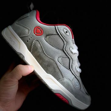 Hand holding a stylish gray and red sneaker with white laces.