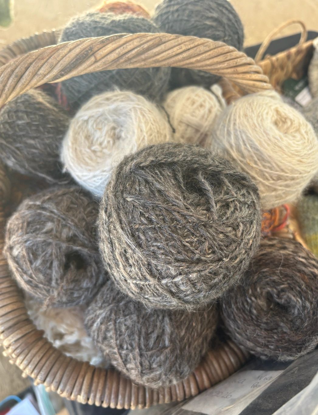 Basket filled with various balls of natural-colored yarn.