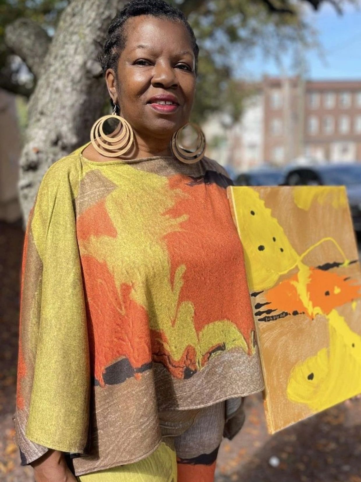 Woman smiling with colorful outfit and artwork.