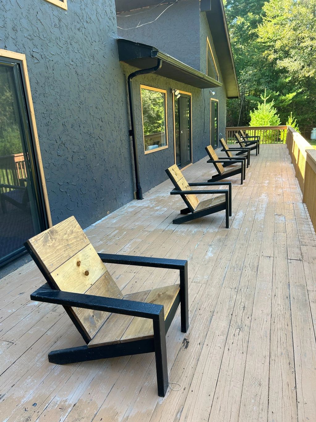 Modern Adirondack Chairs with black frames and stained seat backs.
