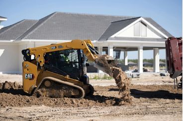 A CAT 255 skid steer loader moving dirt at a construction site.