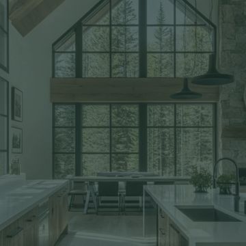 Spacious modern kitchen with large windows overlooking a forest.
