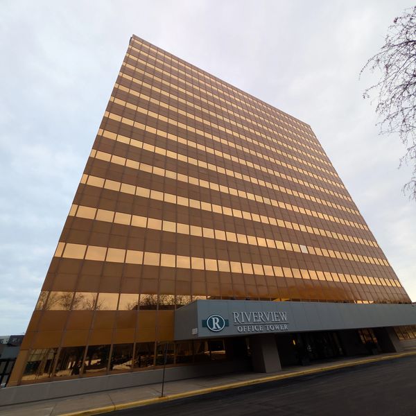 Tall Riverview Office Tower with reflective golden windows under a cloudy sky.