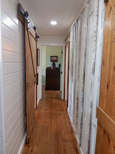 The hallway leads from the kitchen to the bathroom and bedrooms. The original, wide sawtooth, wall