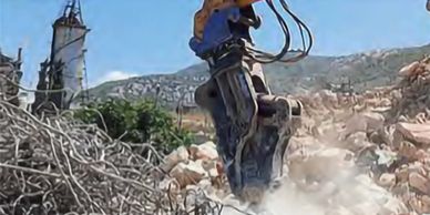 Hydraulic excavator attachment demolishing rocky terrain.