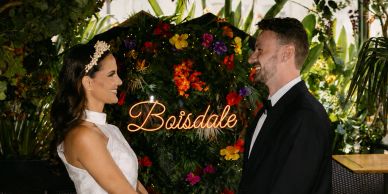 Bride and groom holding hands under floral arch at Boisdale.