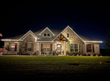 Stone house decorated with white holiday lights at night.