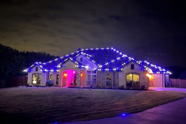 A house decorated with blue and white lights glowing at night.