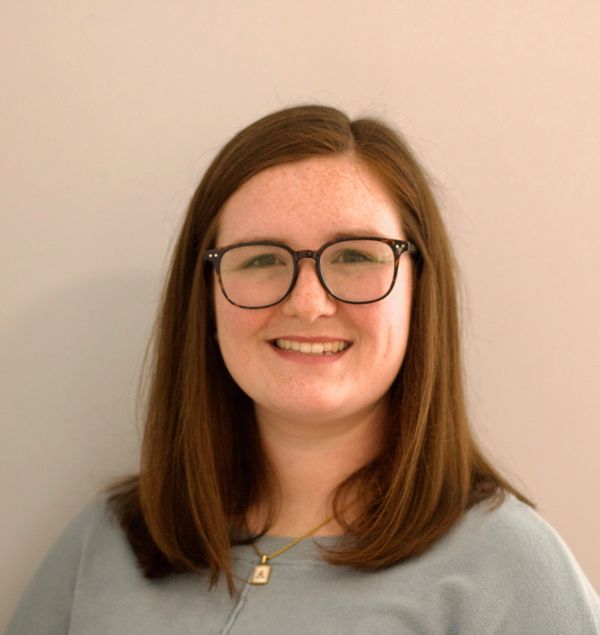 Smiling woman with glasses and shoulder-length brown hair.