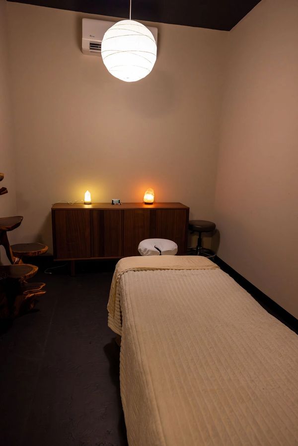 Cozy massage room with dim lighting and a massage table.