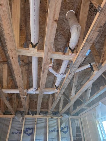 Exposed plumbing and wooden framing in a house under construction.