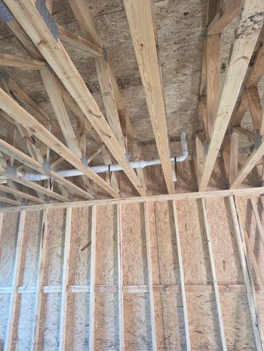 Wooden framing and plumbing inside a building under construction.