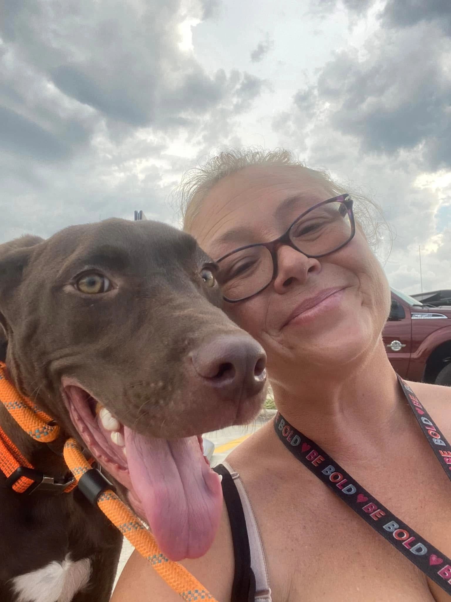 Pet transporter smiling in a selfie with brown dog