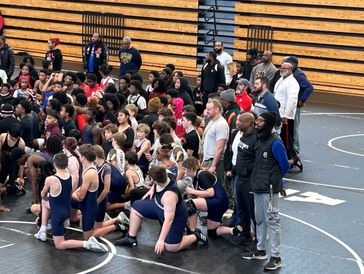 Group photo of wrestlers and coaches in a gymnasium.