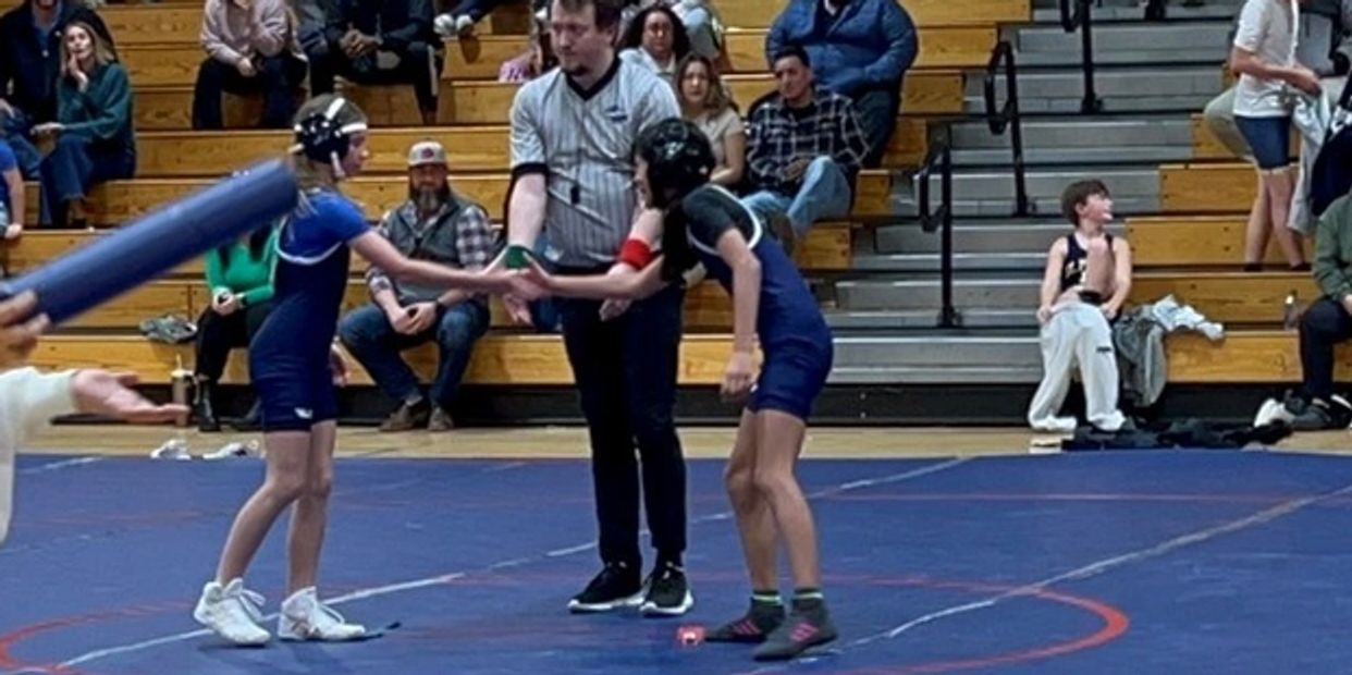 Youth wrestling match with spectators in a gymnasium.