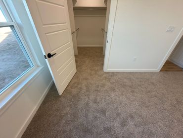 Empty room with beige carpet and an open closet door.