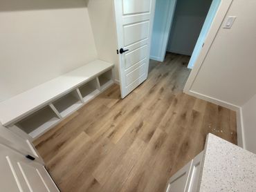 Empty room with wooden floor, white shelves, and an open door.