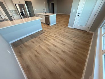 Modern kitchen with wood-style flooring and white countertops.