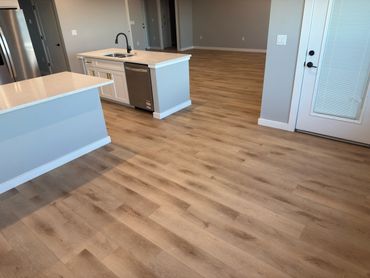 Modern kitchen with light wood flooring and white countertops.