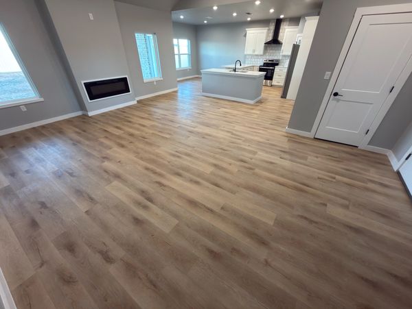 Modern open-concept kitchen and living area with wood flooring and neutral tones.