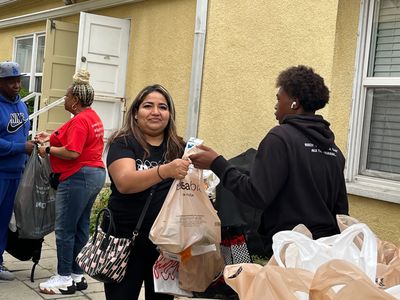 Student volunteer handing groceries to someone in need