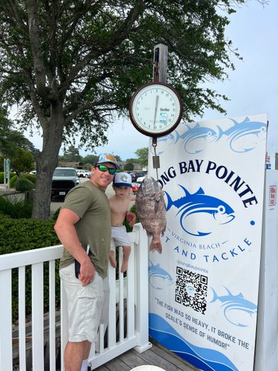 Man and boy posing with a large fish on a scale at Long Bay Pointe Virginia Beach.