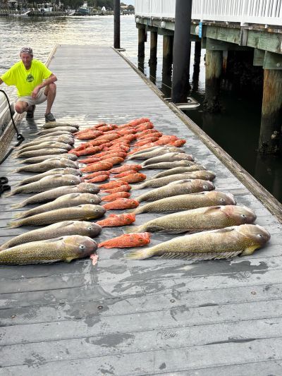 Man poses with a large catch of fish on a dock.