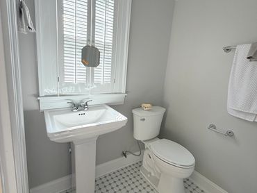 A clean, simple bathroom with a pedestal sink and toilet.