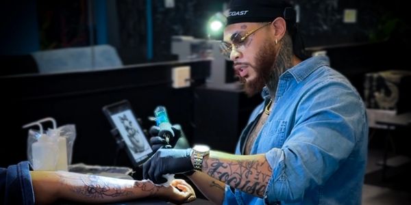 Tattoo artist focused on inking a detailed design on a client's forearm in a modern studio.