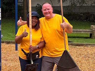 Dan Powell and another volunteer holding rakes at a community playground.