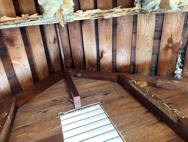 Inside of an attic showing exposed spaced slat boards and wood shingles during a home watch visit.