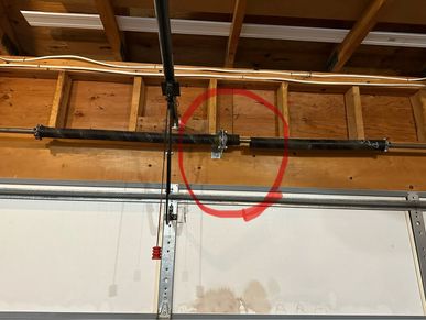 A broken garage door spring found when operating the garage door opener during a home watch visit.