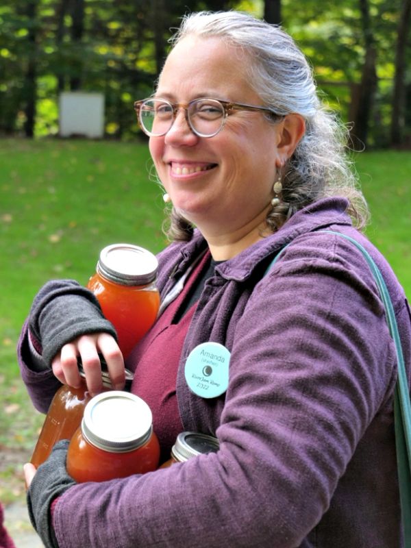 Smiling woman holding jars outdoors.