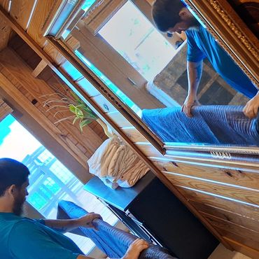 Mover draping a moving blanket over furniture